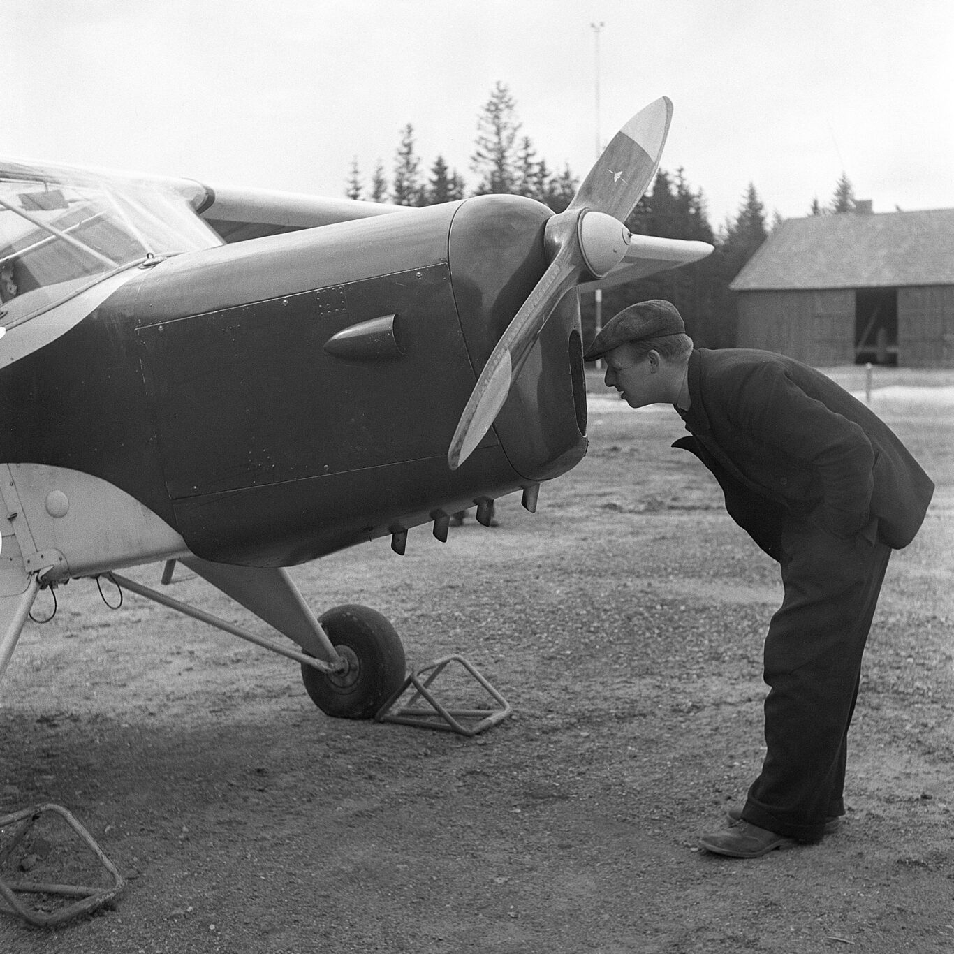 Uomo controlla interno del motore di un aereo leggero.