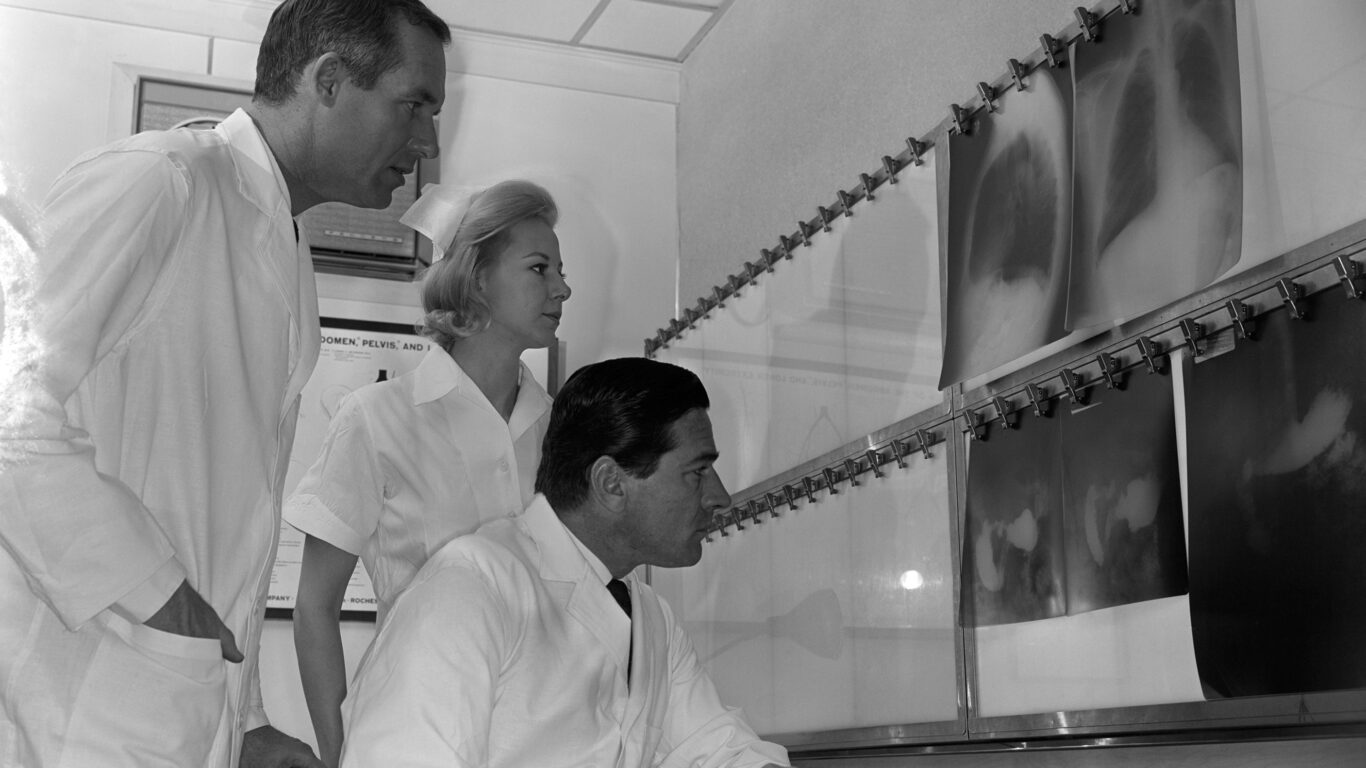Tre dottori osservano le radiografie polmonari di un paziente.